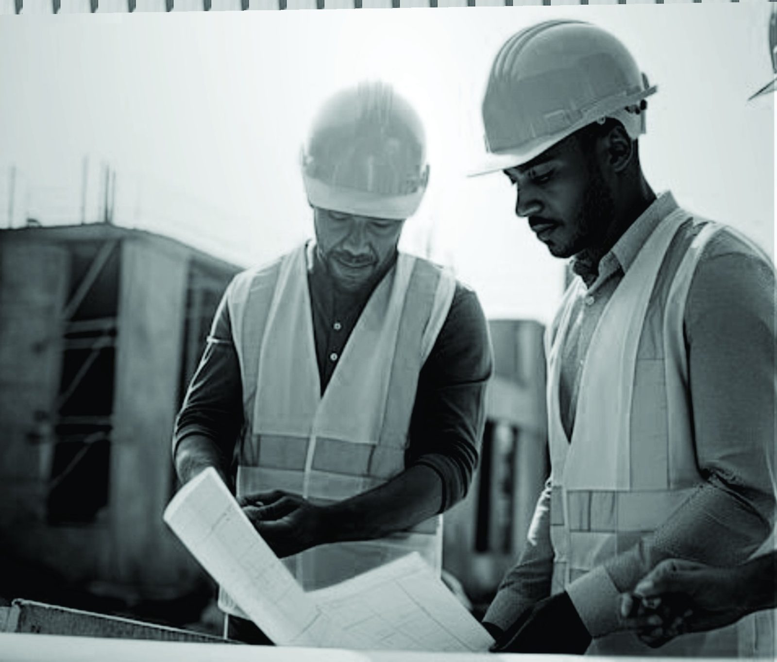 Two professionals in hard hats reviewing plans on site